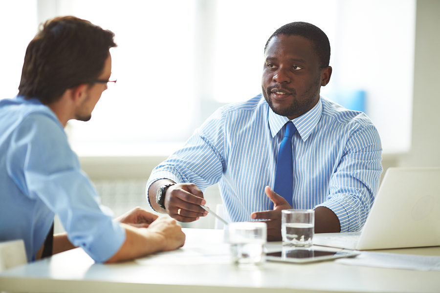Image of two young businessmen interacting at meeting in office